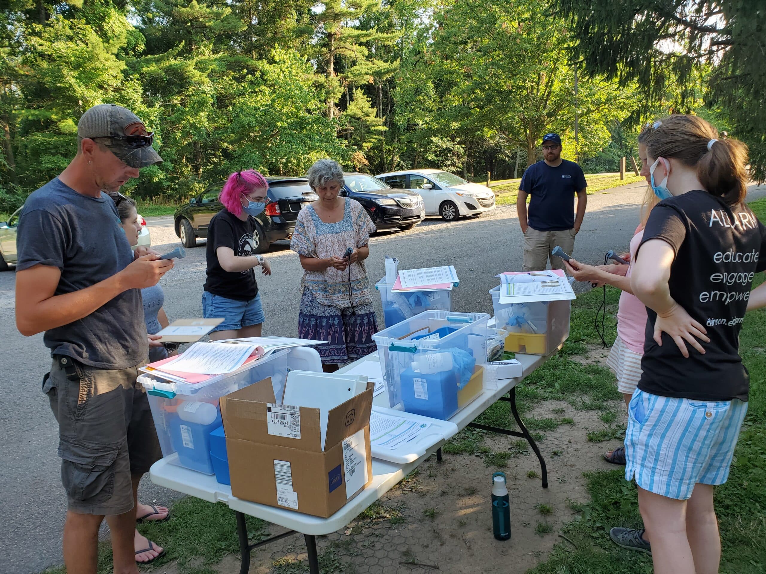 people stand around table with water quality monitoring equipment